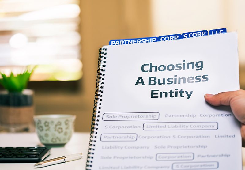 A client at Clearwater Law Group holds a notebook with many business entity types listed, as they get help from a business law attorney deciding which entity is right for them